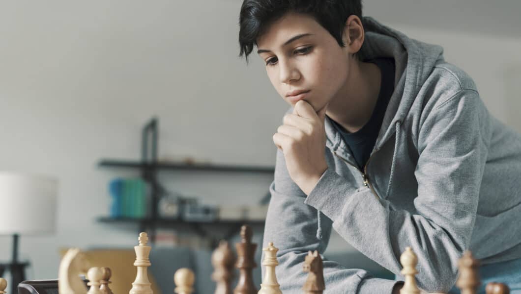 a boy thinking and trying to solve a chess puzzle